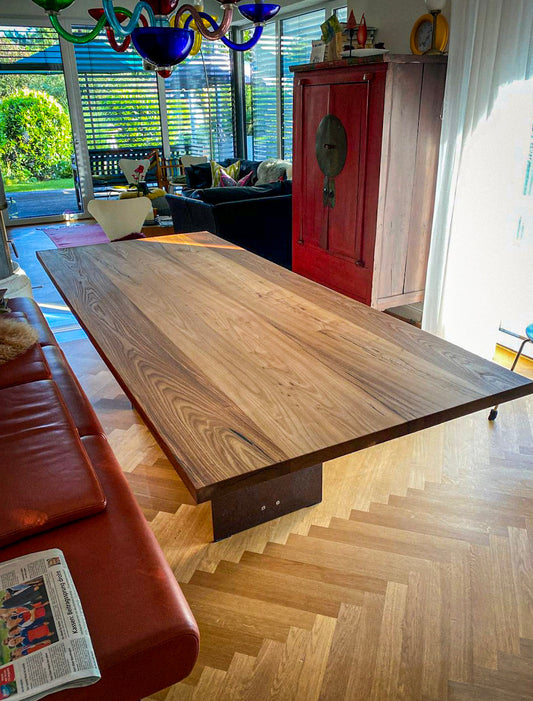 ein Holztisch, der in einem Wohnzimmer neben einem roten Sofa steht