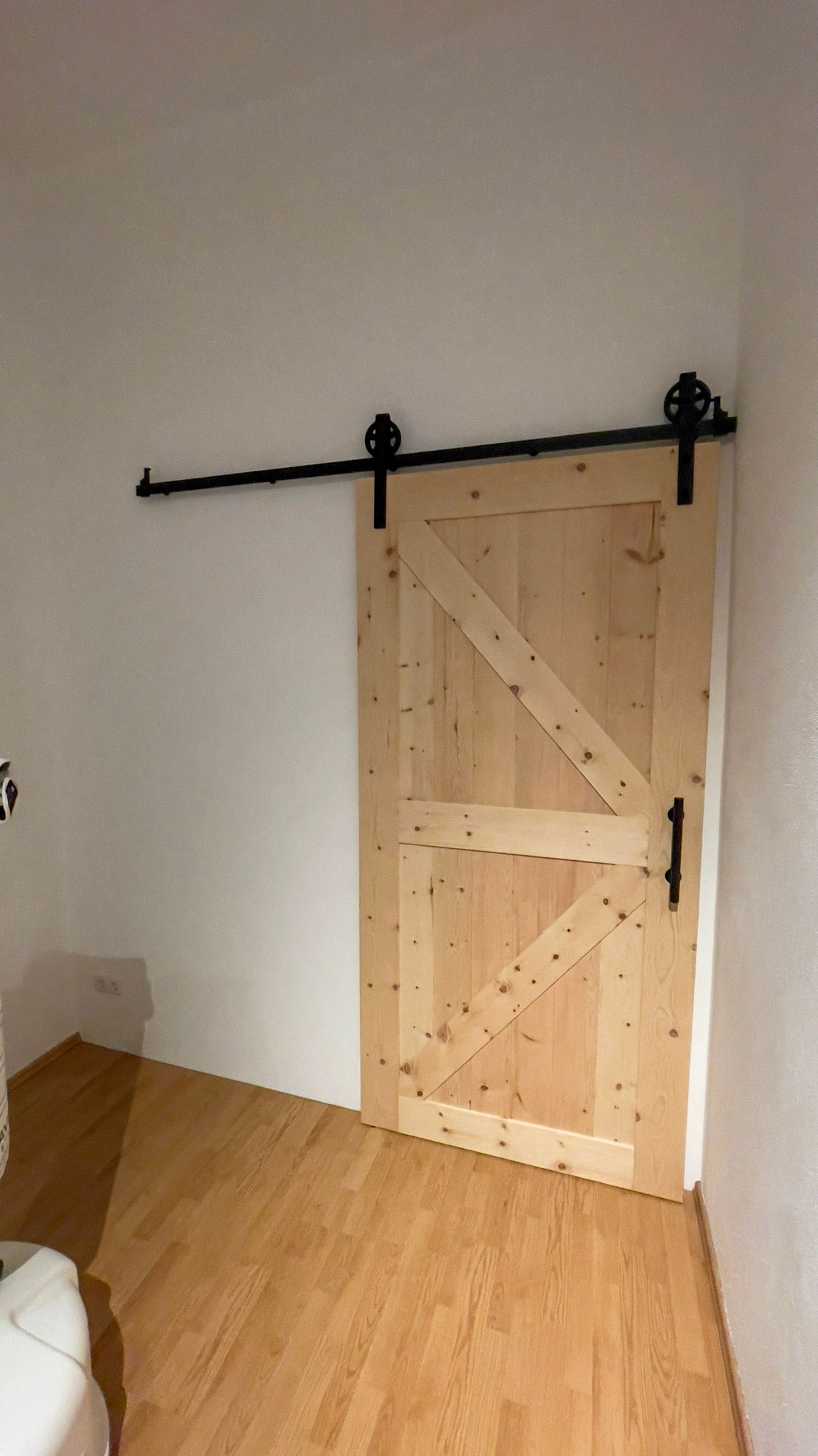 ein Raum mit einer Holztür und einer weißen Toilette