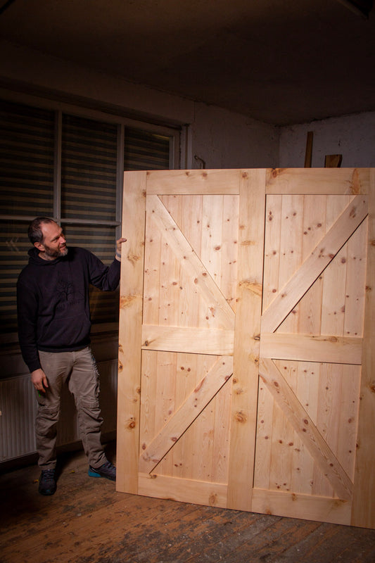 ein Mann steht neben einer großen Holztür