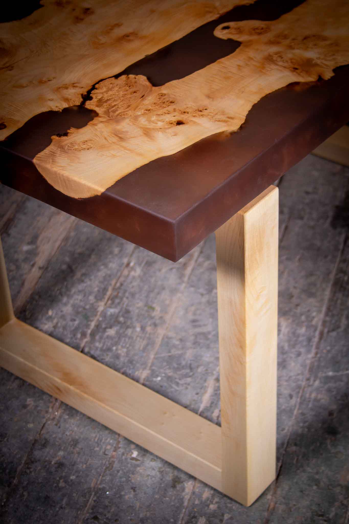 Nahaufnahme des Couchtischs „Anika“ aus Ahornholz mit dem einzigartigen schwarz-transparente Epoxidharz.